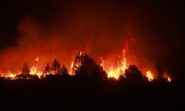 A man waters the roof of his home as the Line Fire burns in the foothills of the San Bernardino Mountains