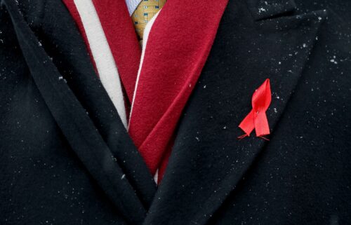 A participant with a red ribbon symbolizing the fight against the HIV virus takes part in a ceremony to mark World AIDS Day near a monument in memory of AIDS victims in Kiev